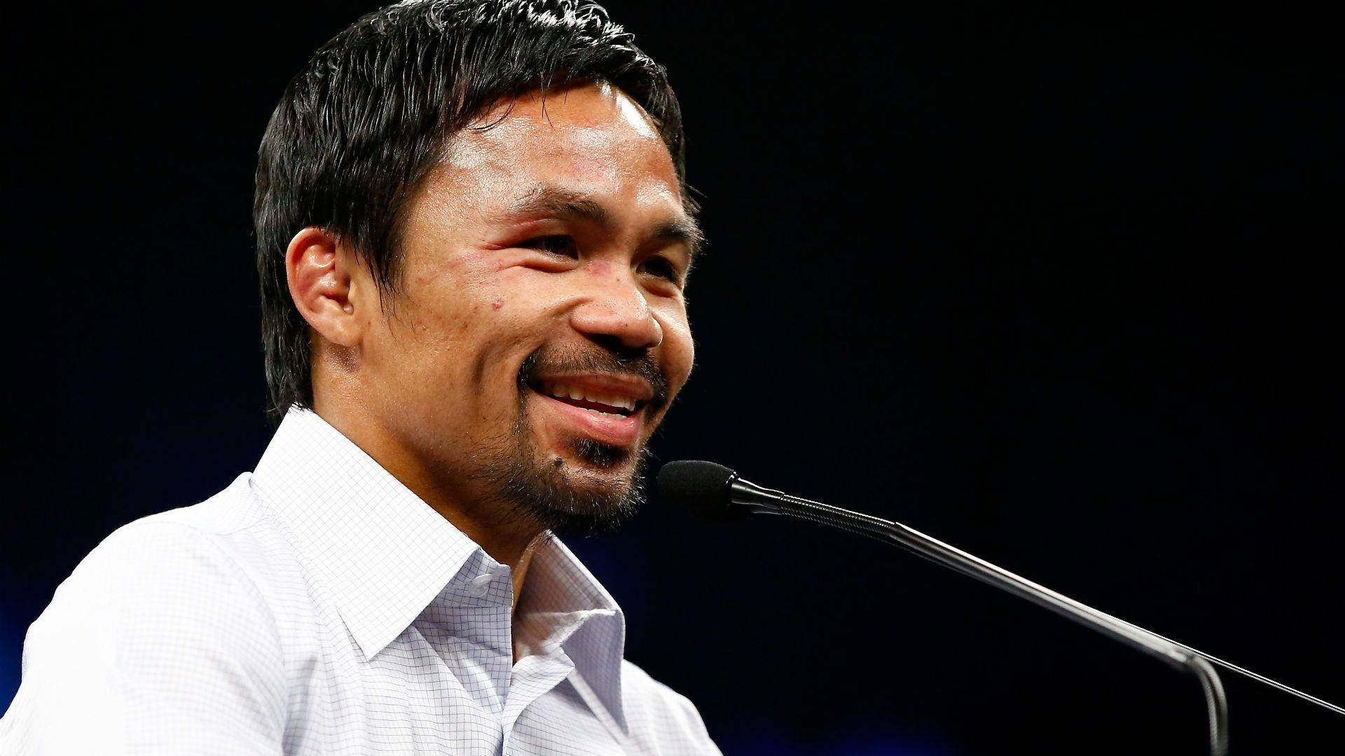 Boxing Legend Manny Pacquiao at Press Conference 壁紙 — 一位微笑的白衫男士對著咪高峰說話，背景深色。