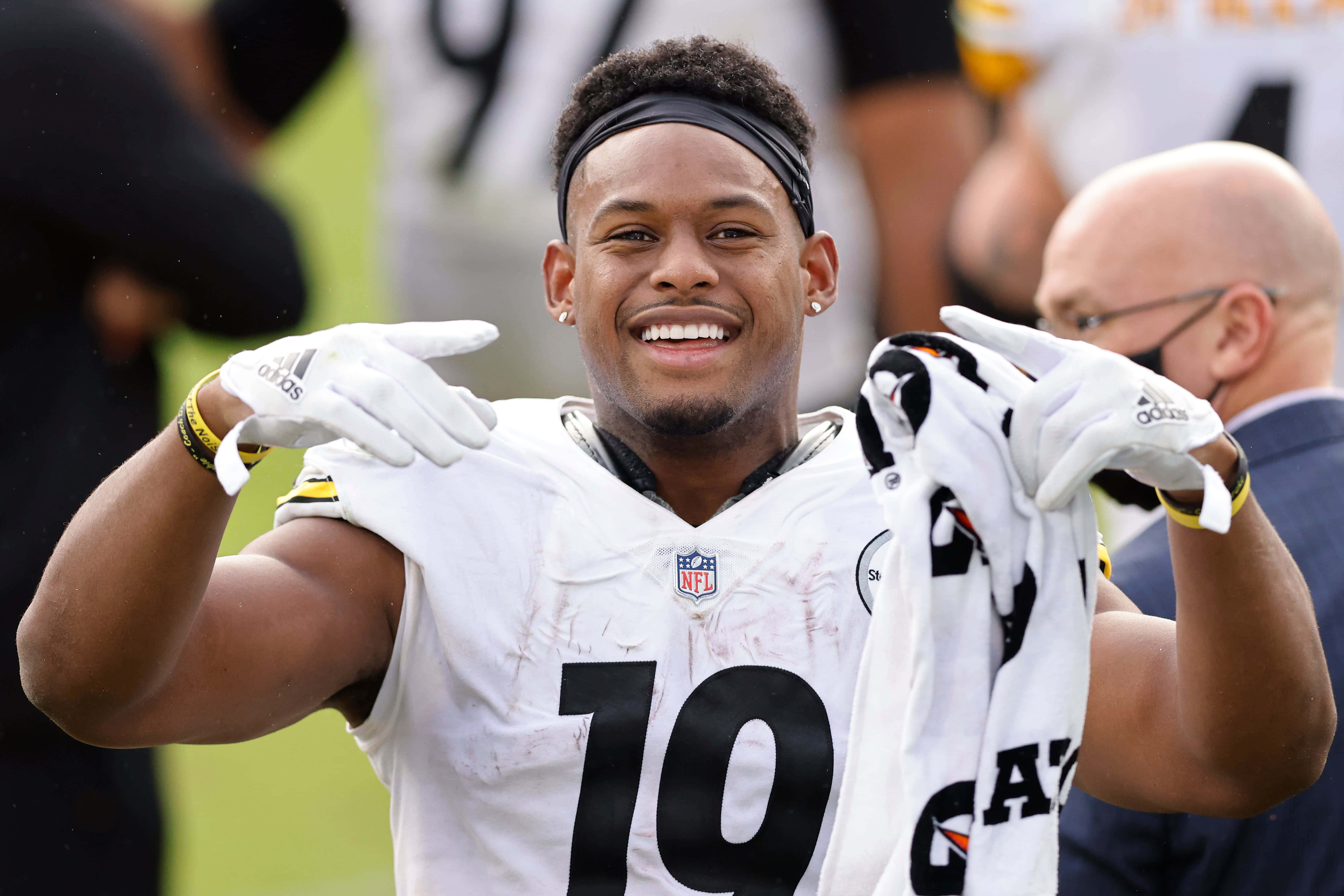 Juju Smith Schuster 桌布 壁紙 — 一位微笑的美式足球員身穿白色球衣，號碼19，在場上慶祝時舉起手套。