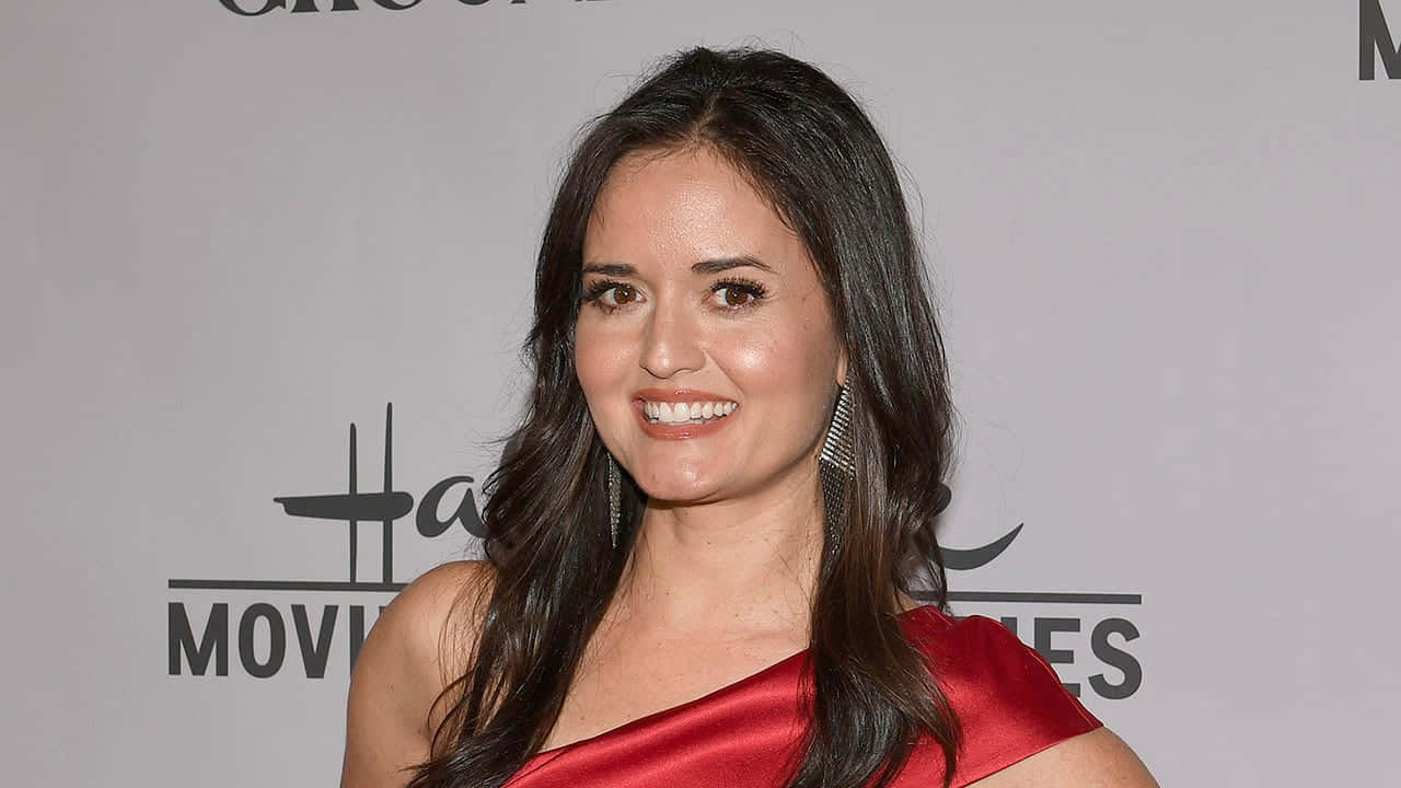 Danica Mckellar 桌布 壁紙 — 一位微笑的長黑髮女性在荷里活活動中穿著鮮紅色緞面連衣裙。