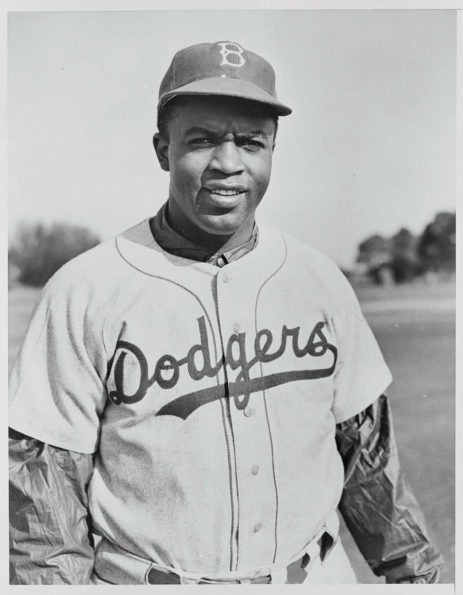 Jackie Robinson 桌布 壁紙 — 一位微笑的黑人棒球運動員身穿道奇隊制服，在復古黑白照片中自信地在戶外擺姿勢。