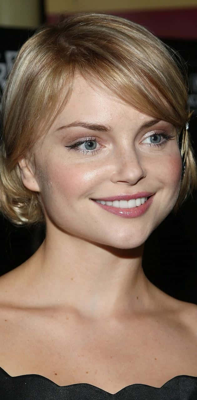 Izabella Miko 桌布 壁紙 — 一位微笑金髮藍眼女性穿著黑色扇貝邊上衣的特寫肖像。