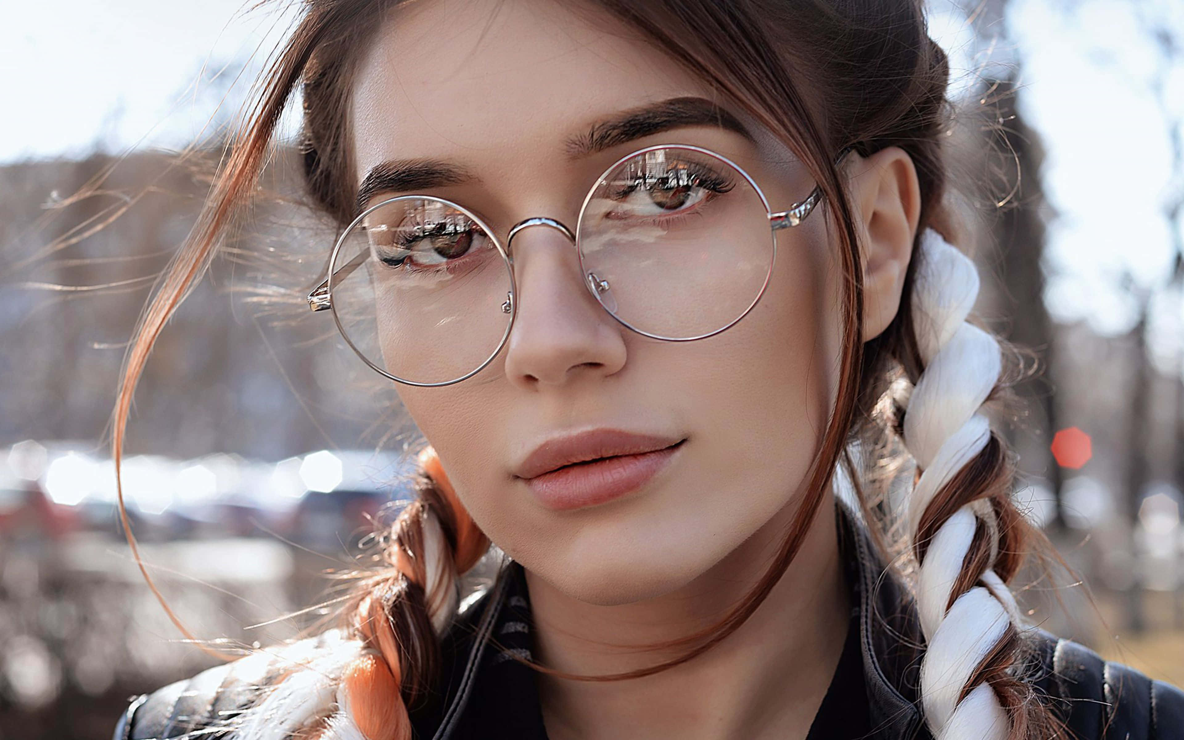 Dua Lipa 桌布 壁紙 — 一位戴圓框眼鏡、辮子頭髮的年輕女性在明亮的陽光下溫柔地凝視戶外。