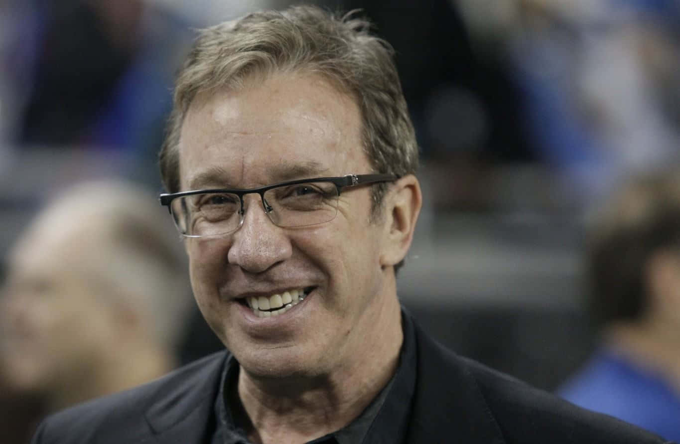 Tim Allen 桌布 壁紙 — 一位戴眼鏡、灰白頭髮、微笑的男士穿著深色西裝外套的特寫照片。