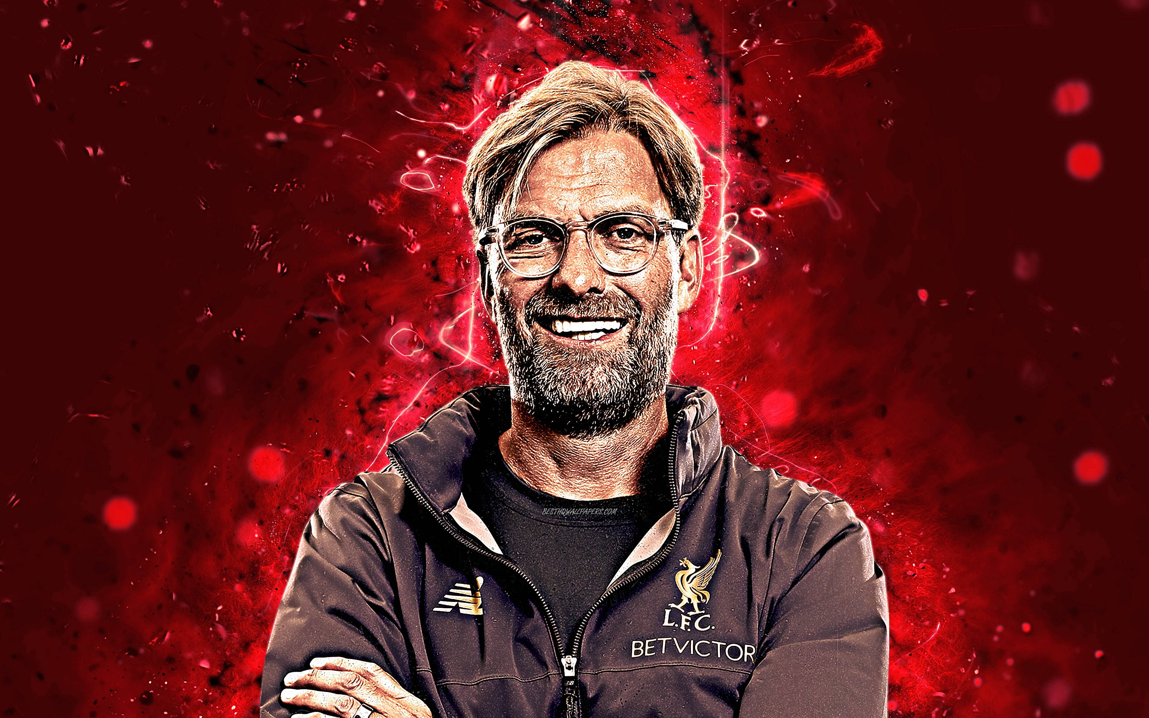 Liverpool Fc 桌布 壁紙 — 一位戴眼鏡、留鬍鬚的 smiling 男士，身穿利物浦FC外套，背景是充滿發光粒子的 vibrant 紅色電氣背景。