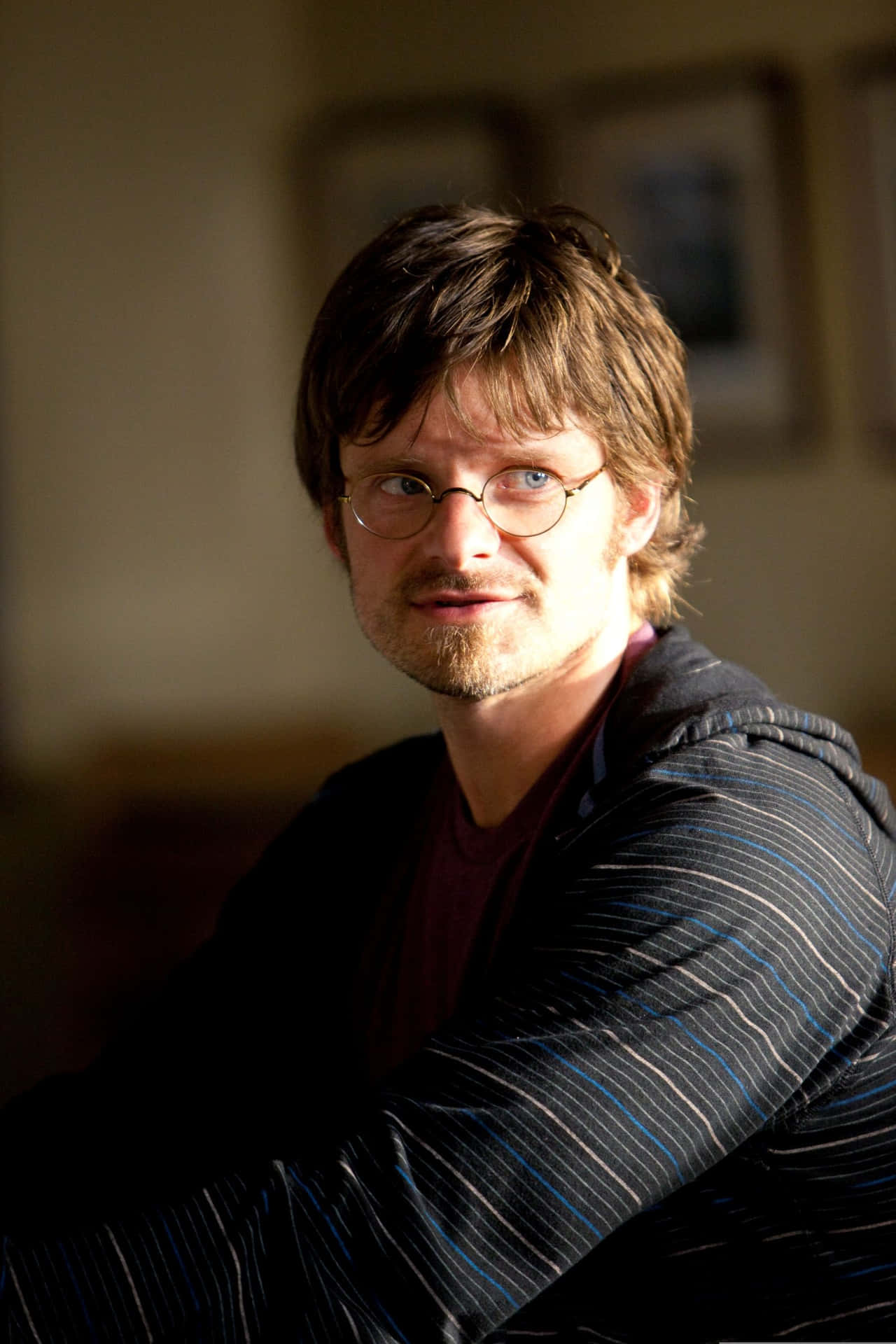Steve Zahn 桌布 壁紙 — 一位戴眼鏡留鬍鬚的男人在柔和光線的室內環境中溫暖地微笑。