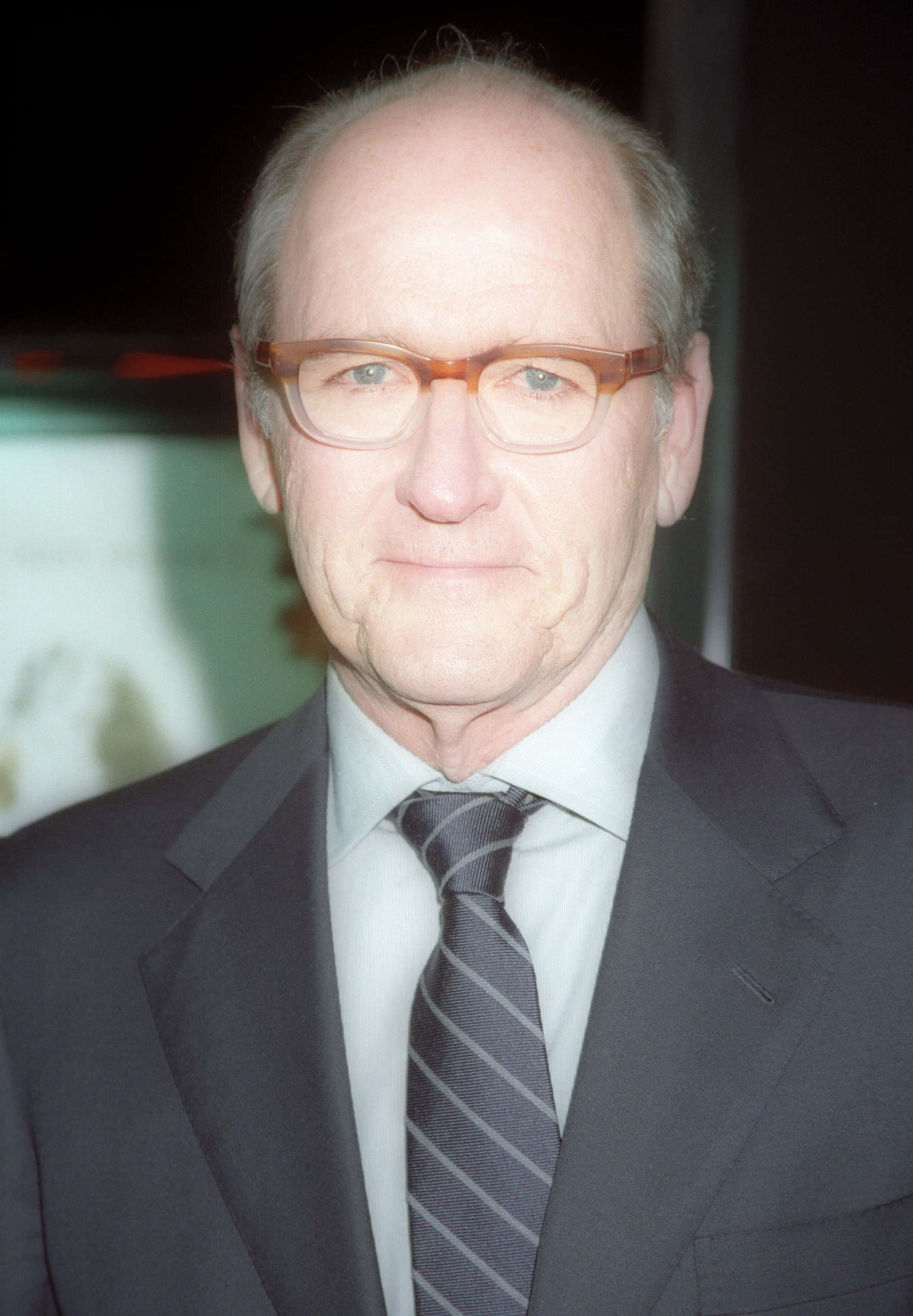Richard Jenkins 桌布 壁紙 — 一位戴眼鏡的中年男子穿著深色西裝和條紋領帶，背景模糊的特寫肖像。