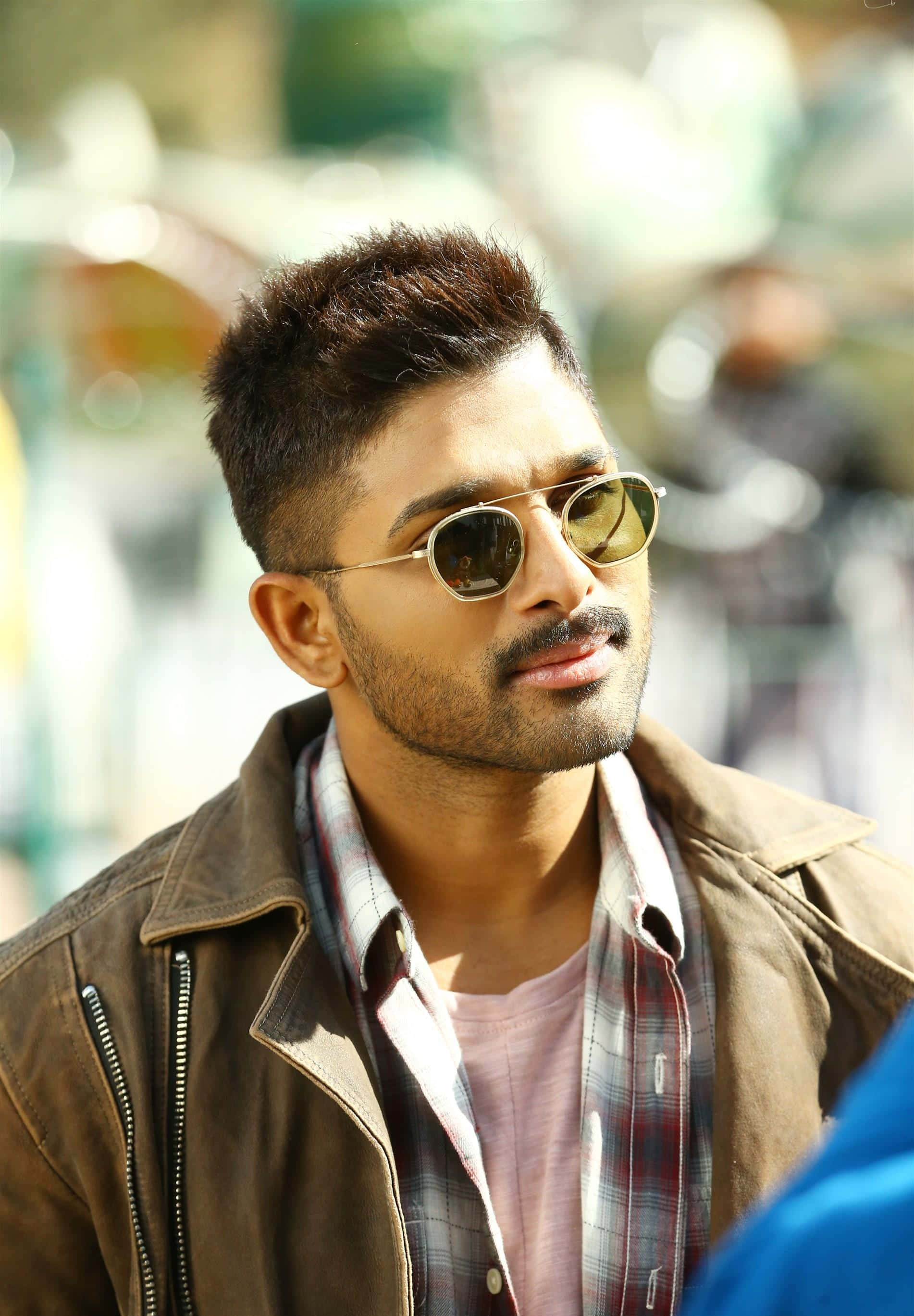 Allu Arjun 桌布 壁紙 — 一位戴著太陽眼鏡和棕色外套的時尚男士，自信地望向陽光普照的街道。