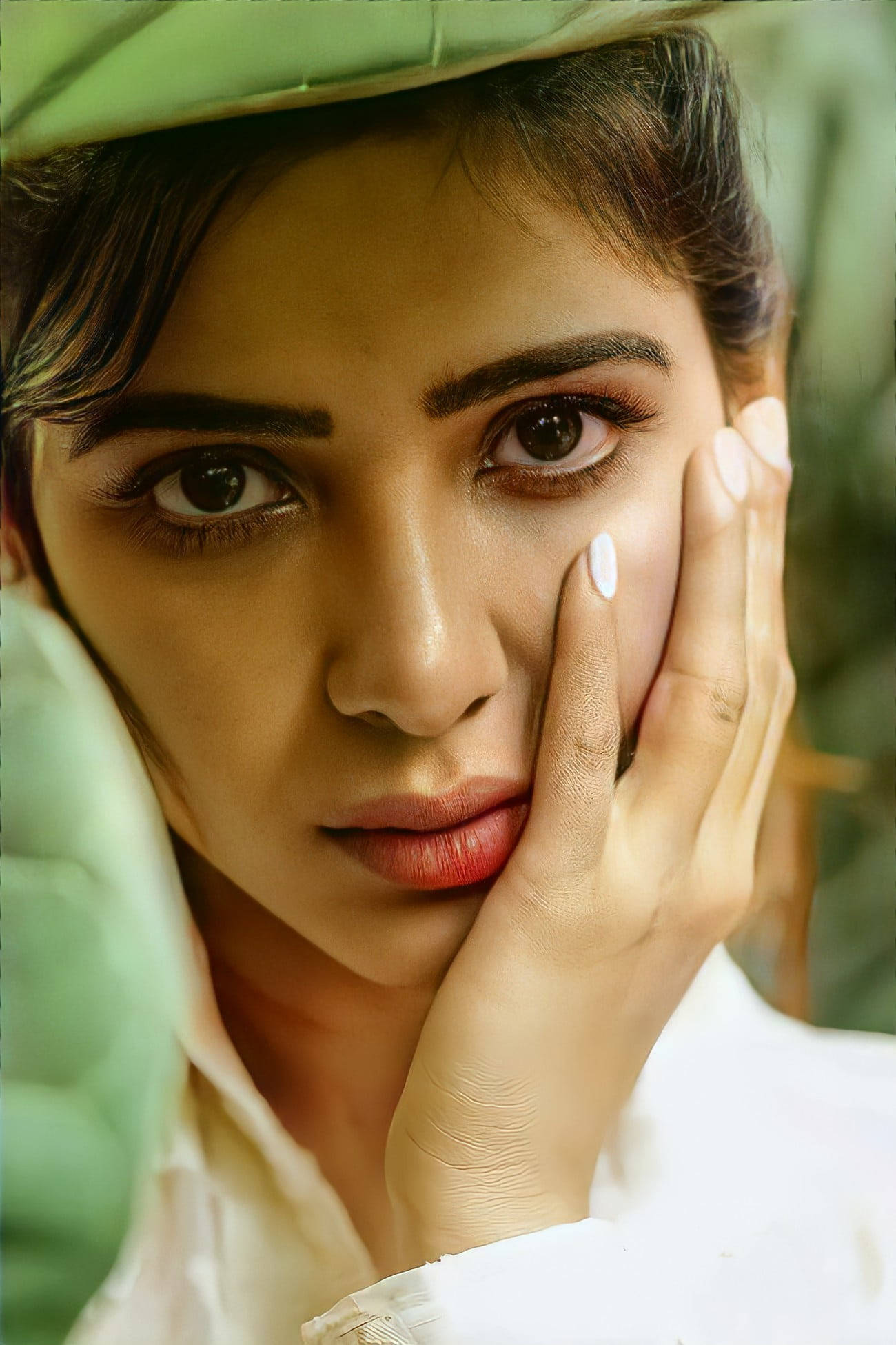 telugu 桌布 壁紙 — 一位戴著綠色帽子的女士，在柔和自然光線下輕輕觸碰臉頰，直視鏡頭。