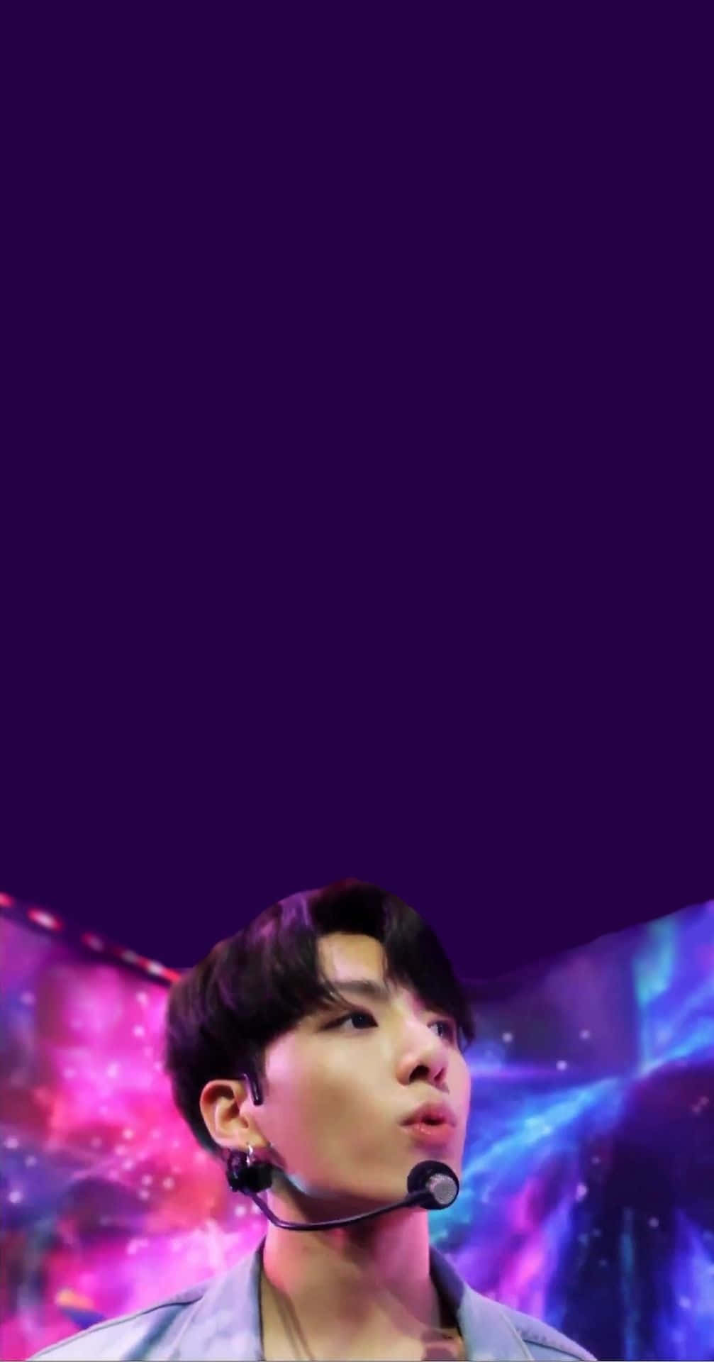 Bts Live 桌布 壁紙 — 一位戴著耳機咪高峰的年輕男子，在充滿活力的宇宙紫色和粉紅色舞台背景下向上凝視。