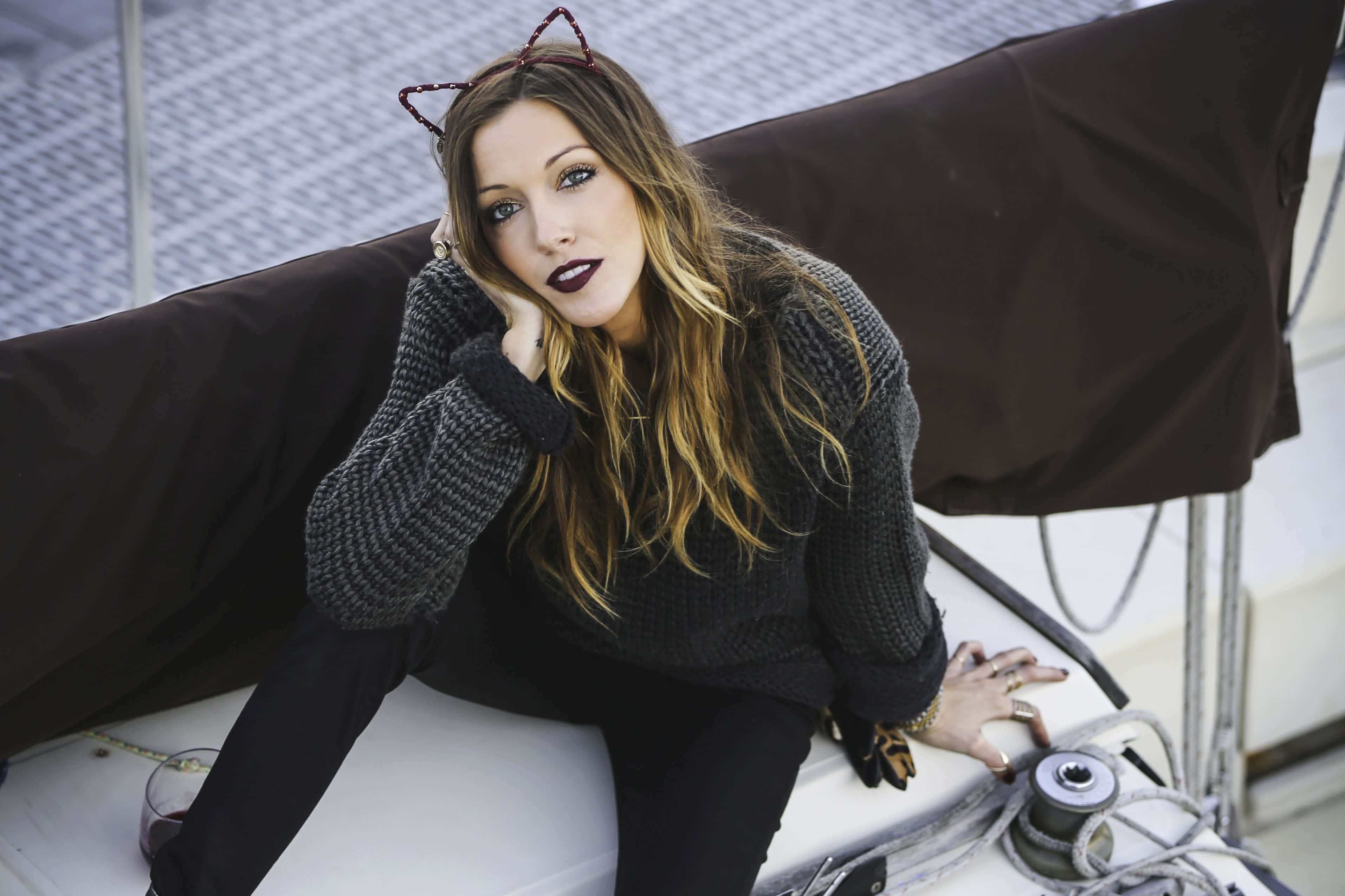katie cassidy 桌布 壁紙 — 一位戴著貓耳和深色唇膏的女人，穿著厚實的針織毛衣，在帆船甲板上閒逛。