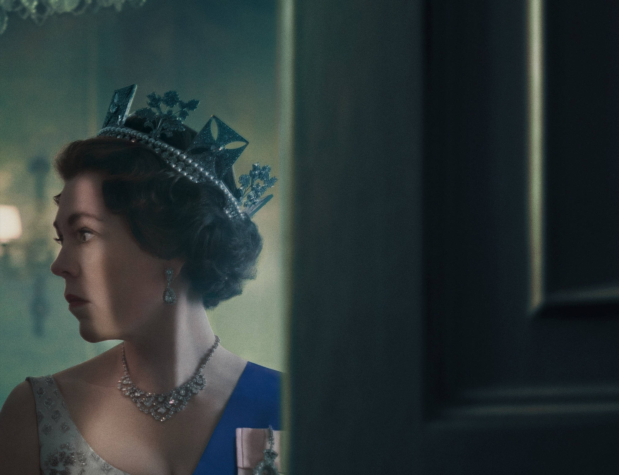 the crown 桌布 壁紙 — 一位戴著鑲嵌珠寶的王冠和項鏈的貴族女性，在光線昏暗的皇家室內，若有所思地透過門口凝視。