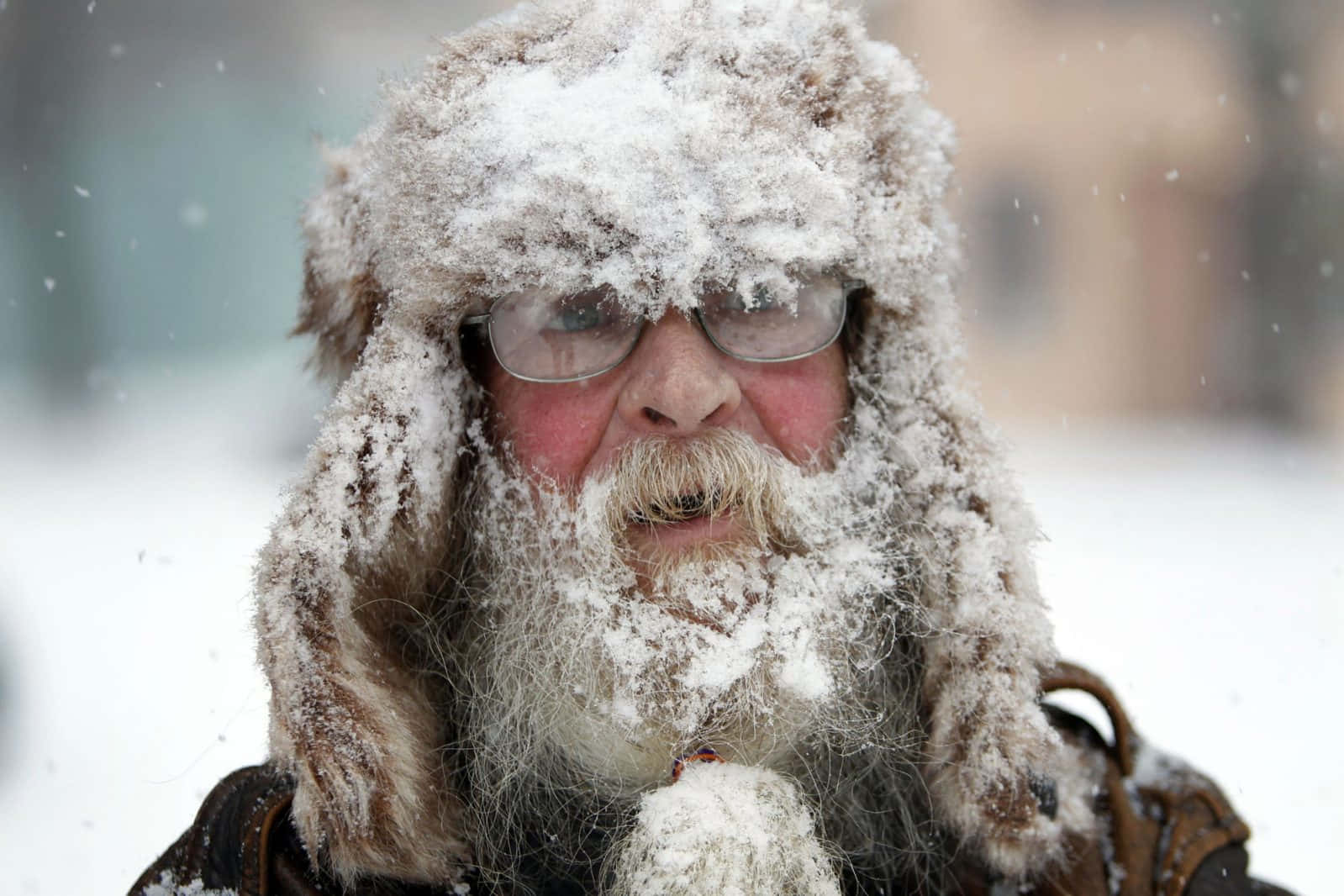 寒冷 桌布 壁紙 — 一位戴著雪覆蓋的毛帽和鬍子的老人站在冬季風暴中，眼鏡起霧，在冷空氣中呼吸可見。