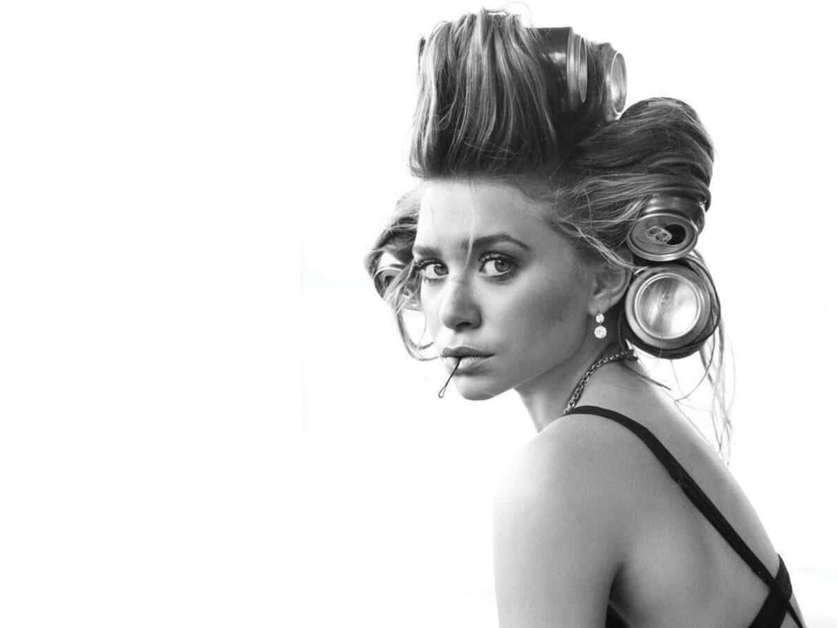 Mary Kate Olsen 桌布 壁紙 — 一位戴著髮捲、嘴裡叼著香煙的女性，在純白背景下以黑白風格強烈凝視。
