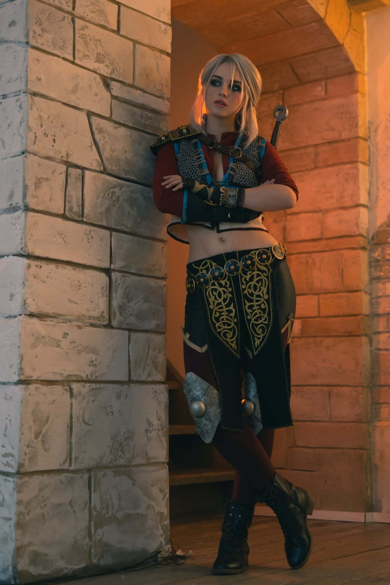 Gaming Cosplay 桌布 壁紙 — 一位扮演傑洛特的cosplayer身穿細節豐富的盔甲，在溫暖的金色光芒中自信地倚靠在石拱門上。