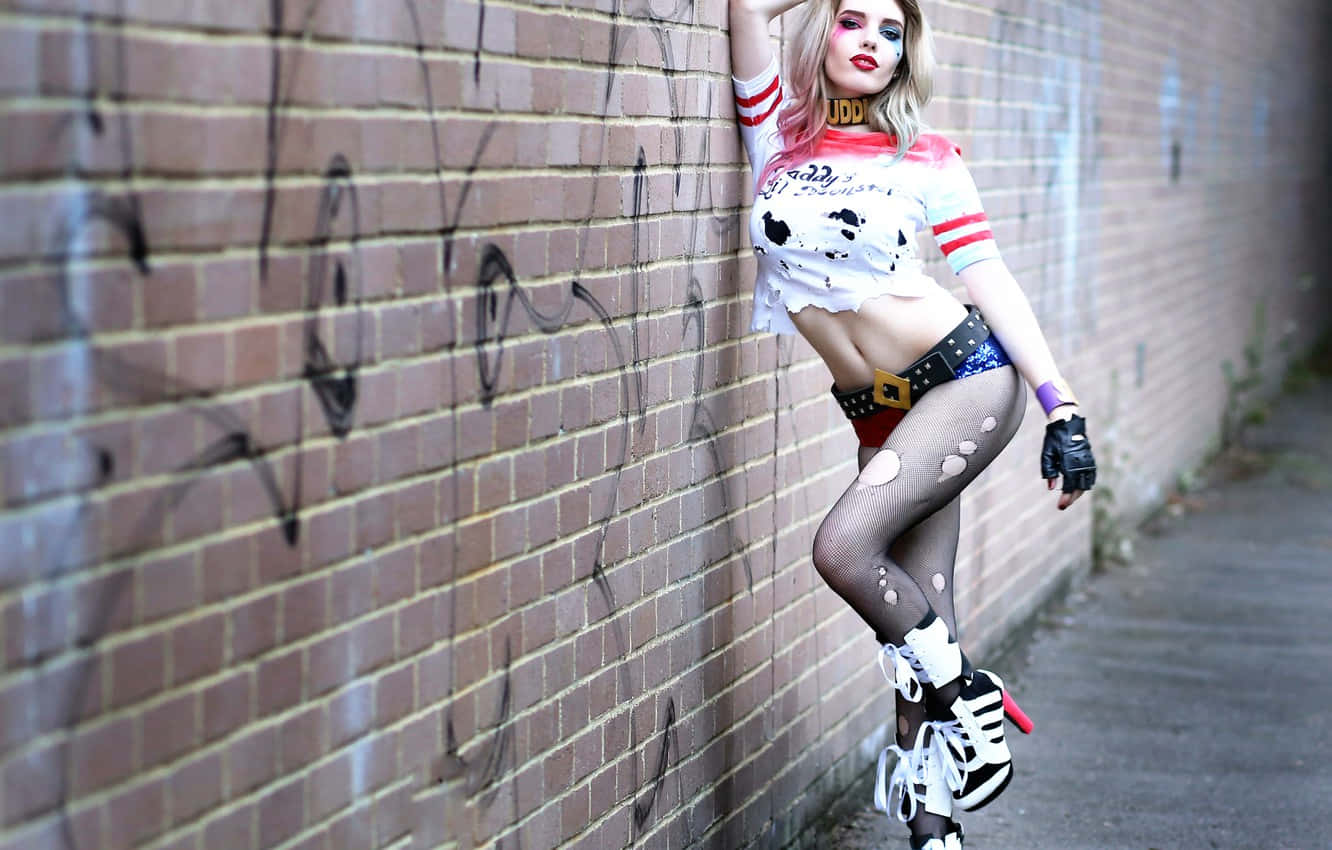 Harley Quinn Cosplay 桌布 壁紙 — 一位扮演哈莉·奎茵的角色扮演者靠在小巷中佈滿塗鴉的磚牆上。