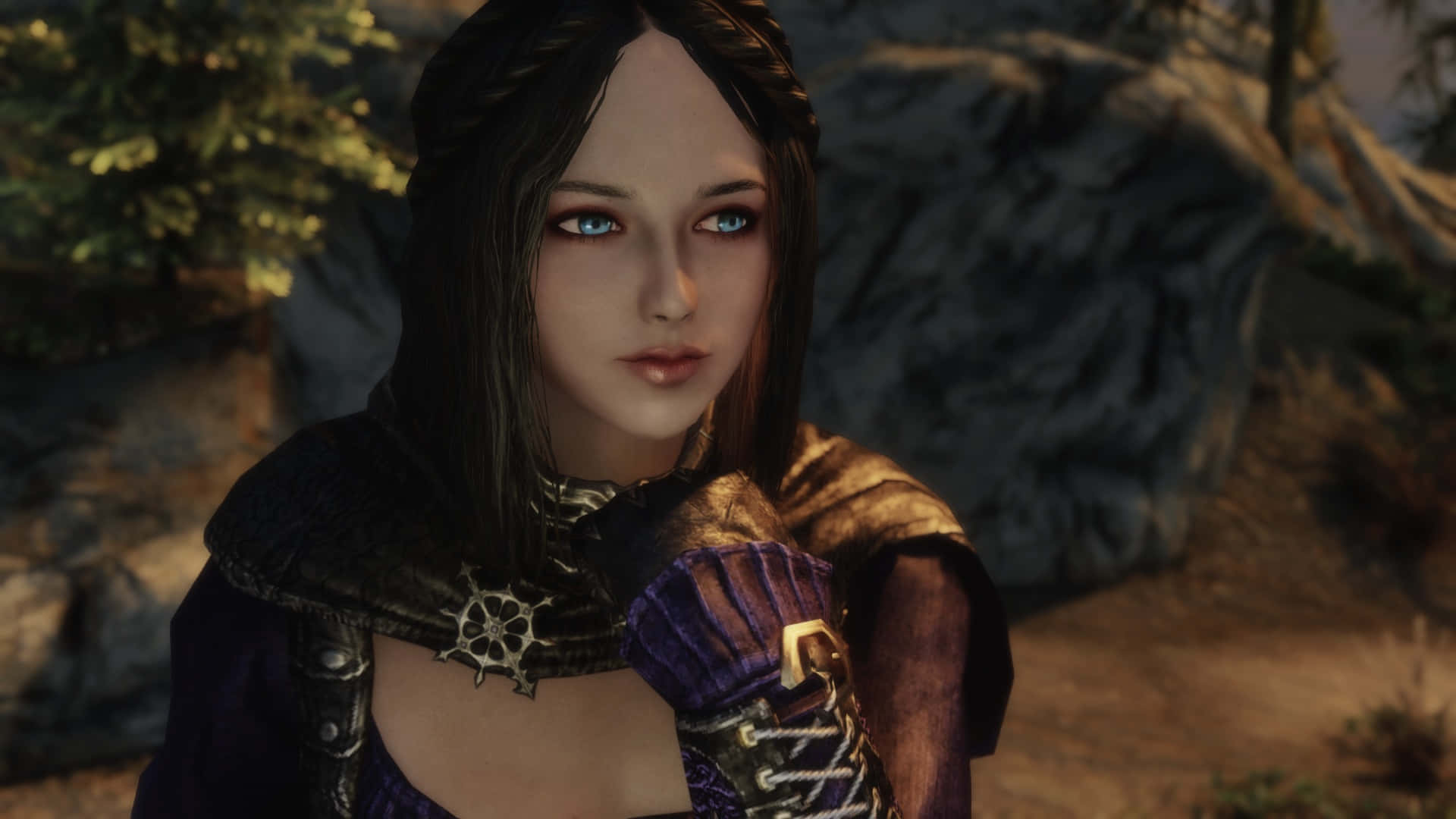 Skyrim Serana 桌布 壁紙 — 一位擁有引人注目的藍色眼睛和編織深色頭髮的奇幻女性，站在岩石戶外環境中，穿著華麗的紫色和金色盔甲。