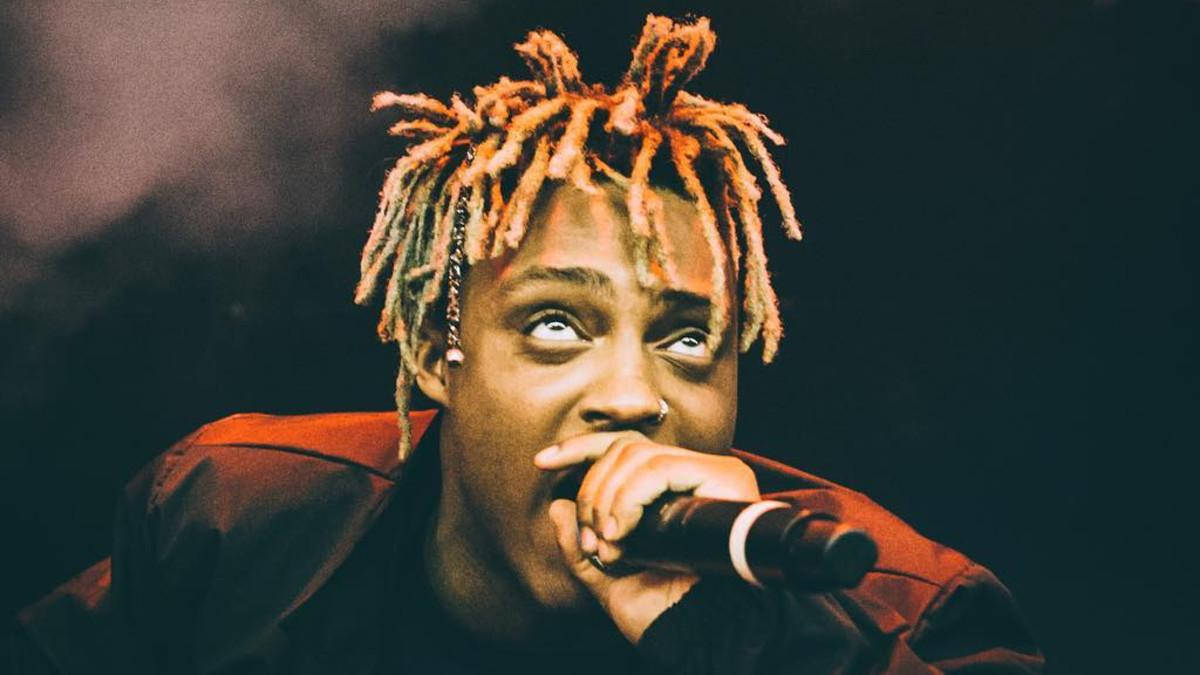 Juice WRLD 桌布 壁紙 — 一位擁有橙色辮子的饒舌歌手在舞台燈光下對著麥克風唱歌的特寫。
