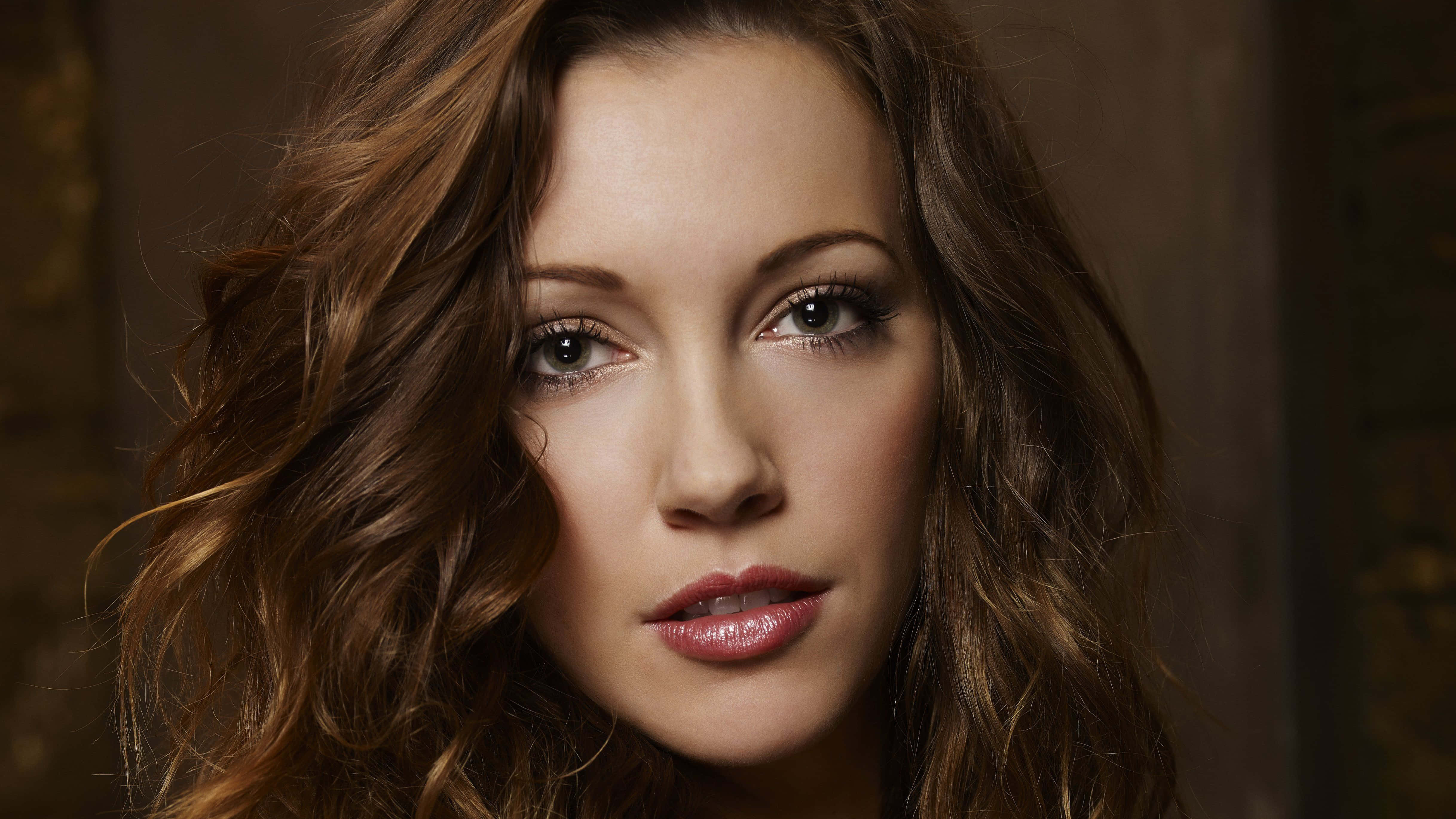 katie cassidy 桌布 壁紙 — 一位擁有波浪棕色頭髮和柔和妝容的女性特寫肖像，直視鏡頭。