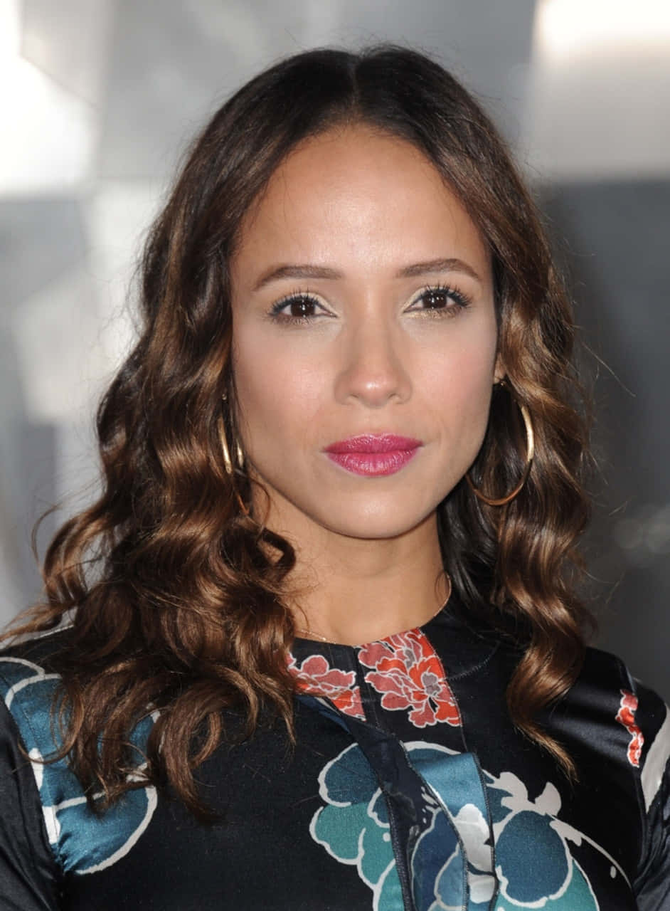 Dania Ramirez 桌布 壁紙 — 一位擁有波浪棕色頭髮和粉紅色唇膏、穿著花卉圖案上衣的女子的特寫肖像。
