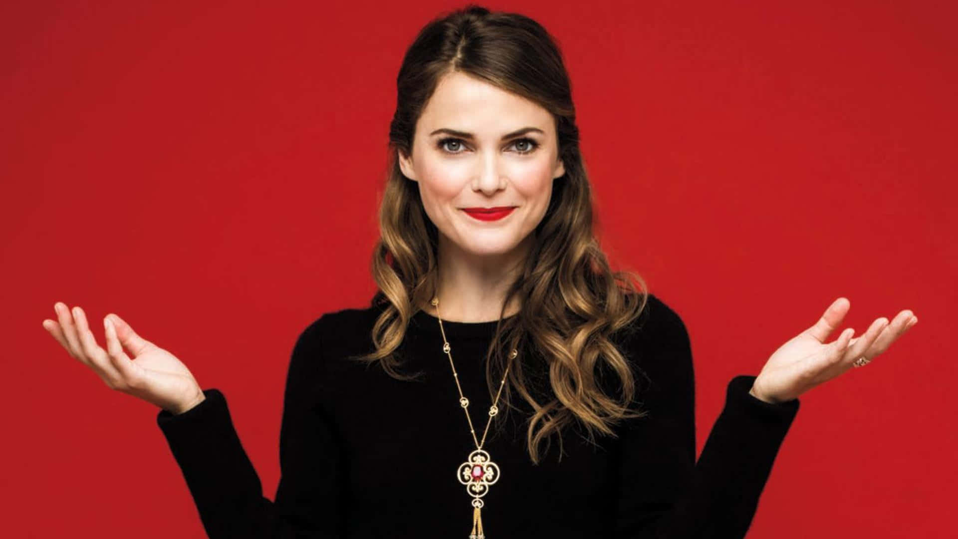 keri russell 桌布 壁紙 — 一位擁有波浪棕色頭髮和紅色唇膏的女性，在純紅色背景前張開雙手聳肩。