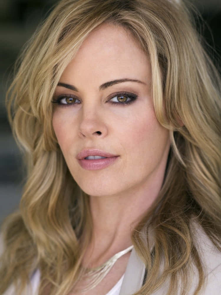 Chandra West 桌布 壁紙 — 一位擁有波浪金髮和煙燻眼妝的女性近距離肖像，直視鏡頭。
