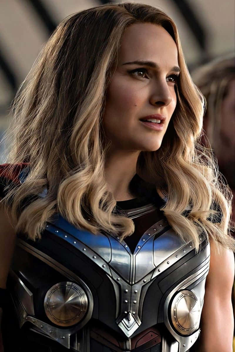Jane Foster 桌布 壁紙 — 一位擁有波浪金髮的女性特寫，身穿帶有圓形金屬板的精緻銀藍色盔甲。
