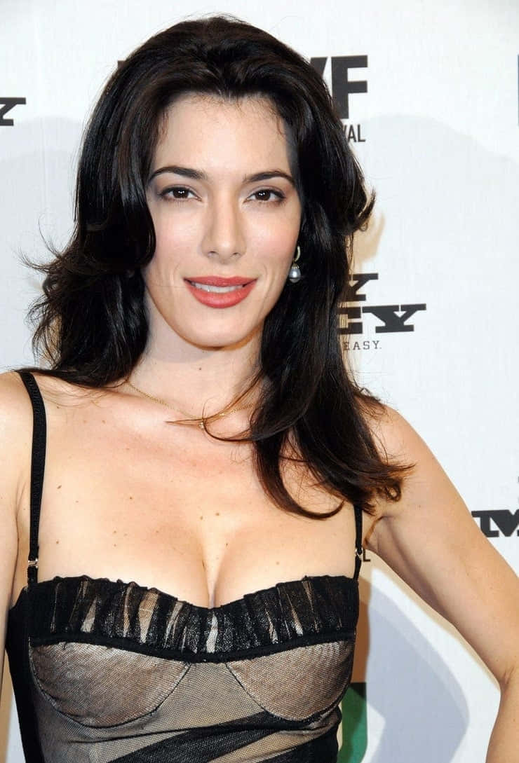 Jaime Murray 桌布 壁紙 — 一位擁有深色波浪長髮的女性在電影節活動中穿著黑色透視上衣對著鏡頭微笑。