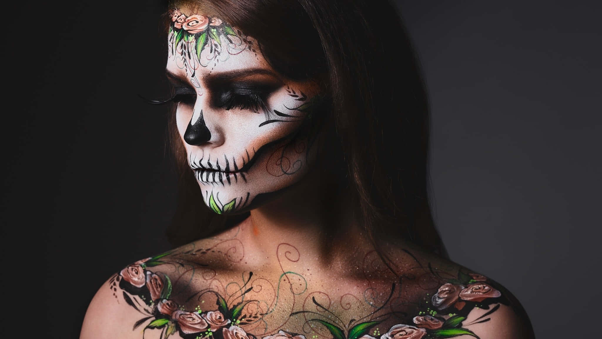 Halloween Tattoos 桌布 壁紙 — 一位擁有精緻糖骷髏妝容和花卉紋身的女性，在黑暗背景中閃耀。