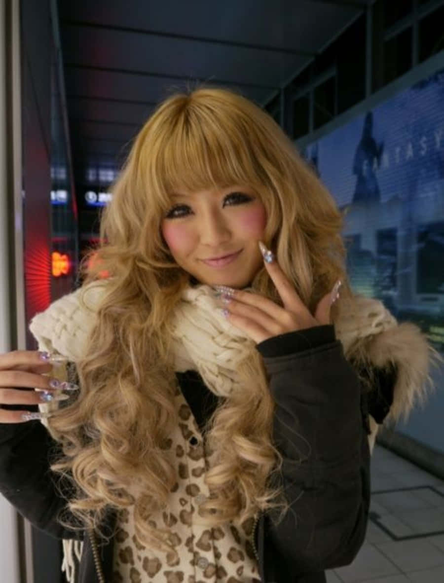 Gyaru 桌布 壁紙 — 一位擁有金色長捲髮和閃亮指甲的年輕女性，在夜晚的城市中穿著豹紋上衣和毛絨圍巾，愉快地擺姿勢。