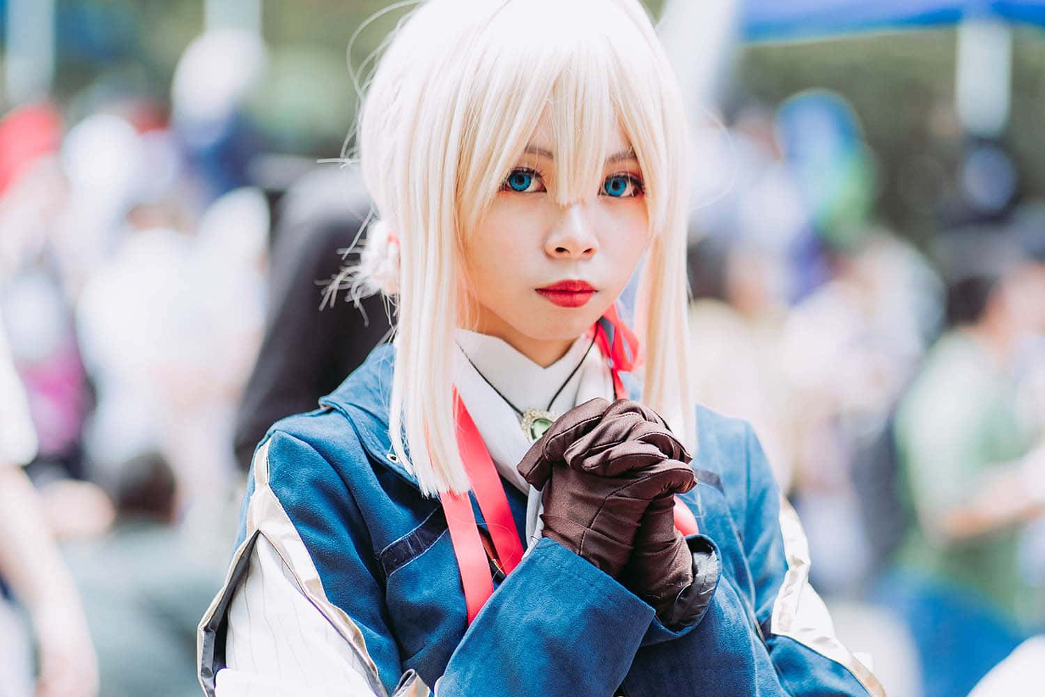 Otaku Culture 桌布 壁紙 — 一位擁有鉑金色頭髮和引人注目的藍色眼睛的角色扮演者，穿著詳細的藍白服裝，搭配棕色手套和紅色絲帶。