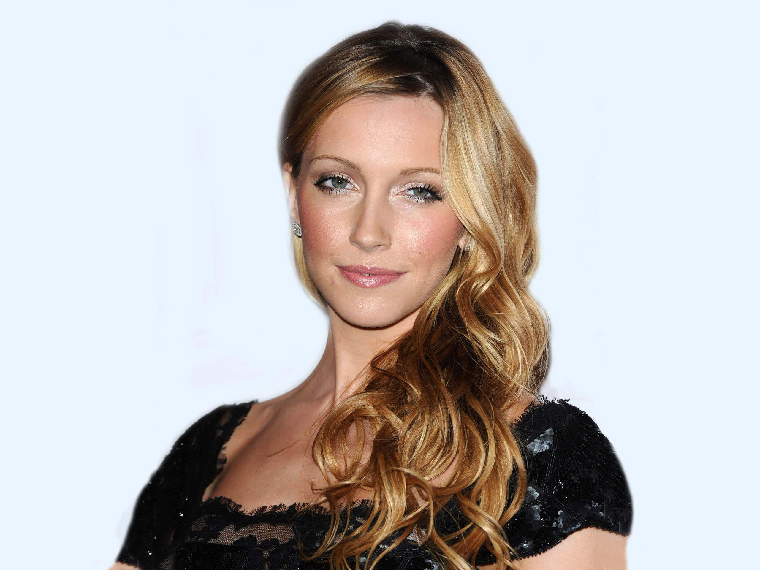 katie cassidy 桌布 壁紙 — 一位擁有長波浪金髮和綠色眼睛的女性，穿著黑色蕾絲上衣，背景為淺藍色。
