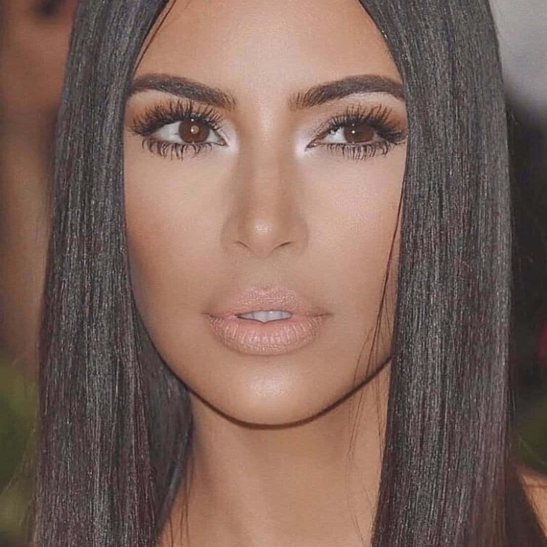 Kim Kardashian 桌布 壁紙 — 一位擁有長直黑髮和戲劇化妝容的女性直視鏡頭的特寫肖像。