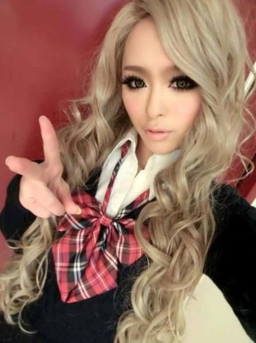 Gyaru 桌布 壁紙 — 一位擁有長長金色捲髮和戲劇化妝容的年輕女性，在紅色背景前擺出和平手勢。
