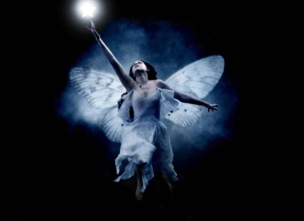Cute Fairy 桌布 壁紙 — 一位擁有飛蛾翅膀的女性在黑暗煙霧繚繞的背景中向上伸向一顆發光的星星。