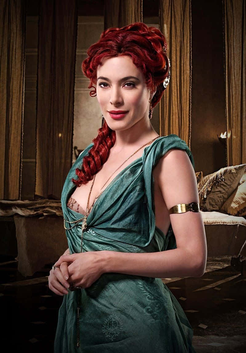 Jaime Murray 桌布 壁紙 — 一位擁有鮮艷紅色辮子頭髮的女性，在裝飾華麗的室內穿著優雅的綠色天鵝絨長袍。