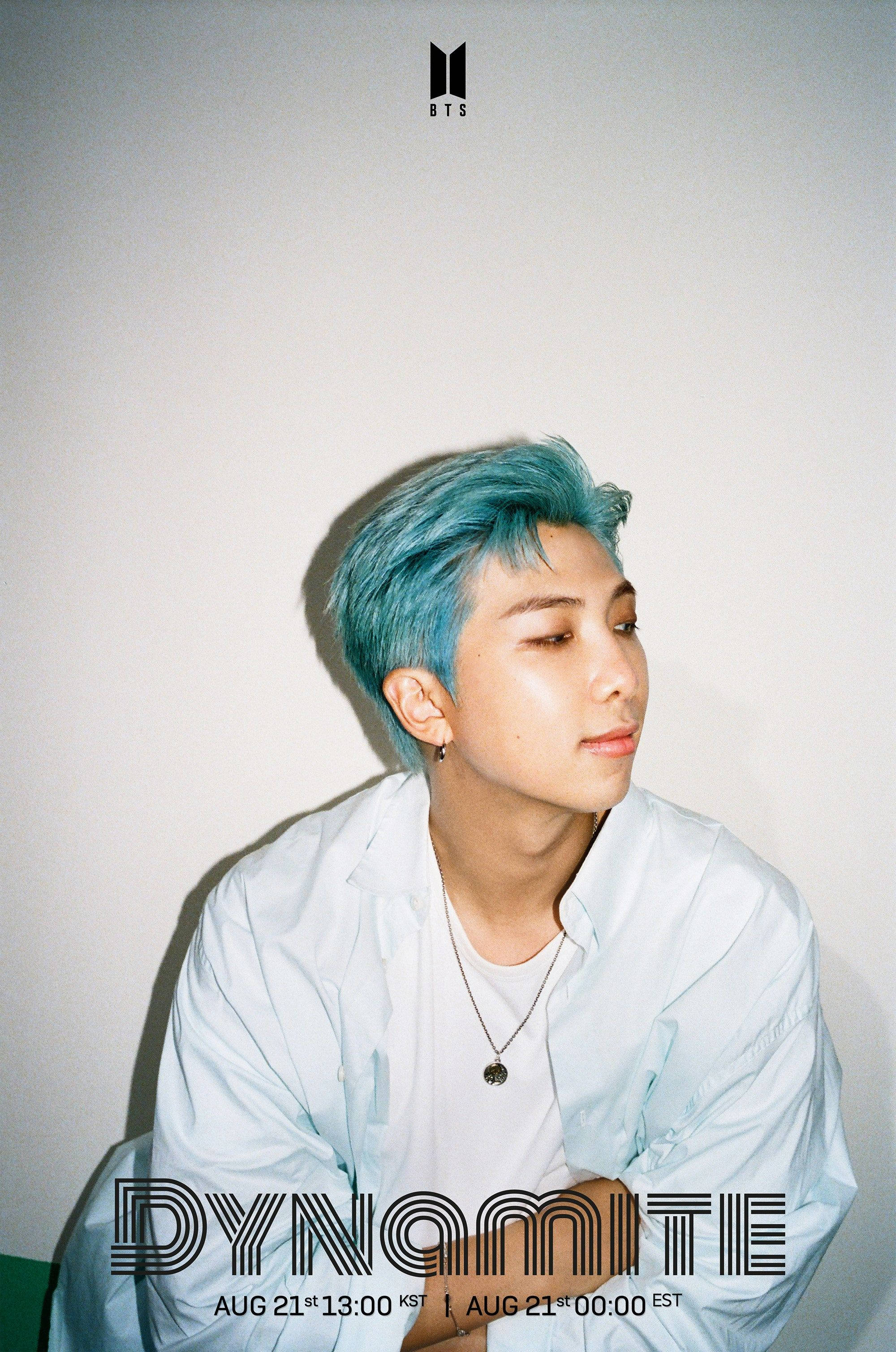 Rm 桌布 壁紙 — 一位擁有鮮豔藍色頭髮的年輕男子，在柔和光線下穿著淺藍色襯衫，靠著素色牆壁坐著。