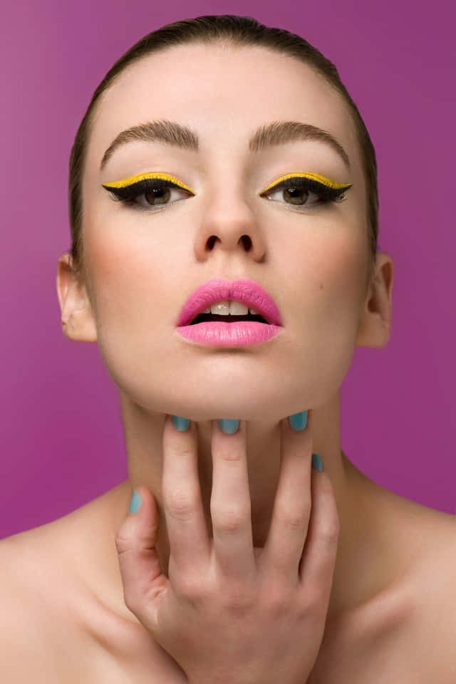 Spring Makeup 桌布 壁紙 — 一位擁有鮮黃色翼狀眼線和粉紅嘴唇的女性，在鮮豔的紫色背景前凝視前方。