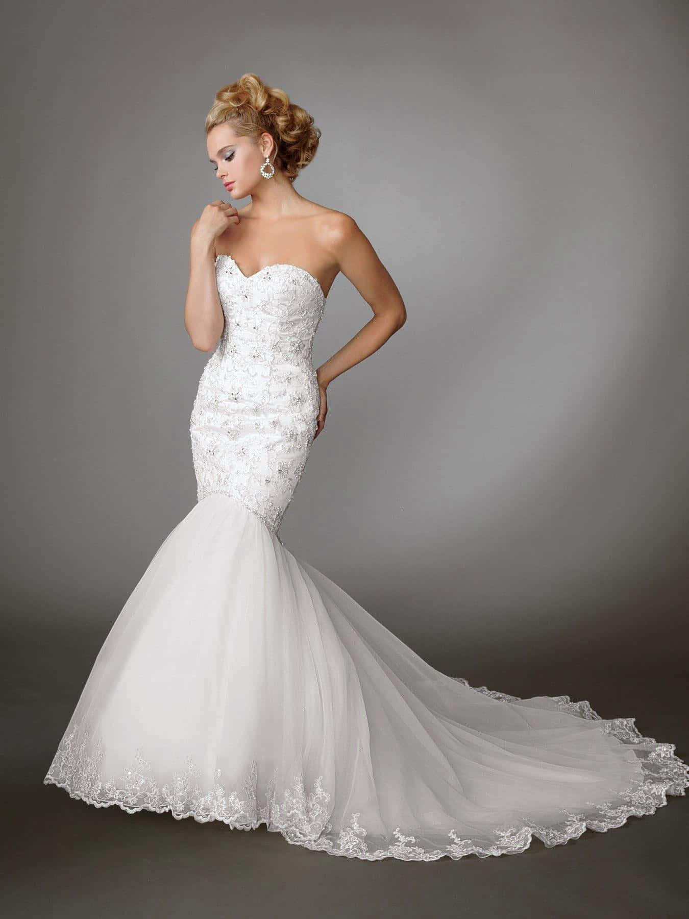 Wedding Dress 桌布 壁紙 — 一位新娘穿著優雅的白色美人魚婚紗，帶有蕾絲細節，在柔和的灰色工作室背景下優雅地擺姿勢。