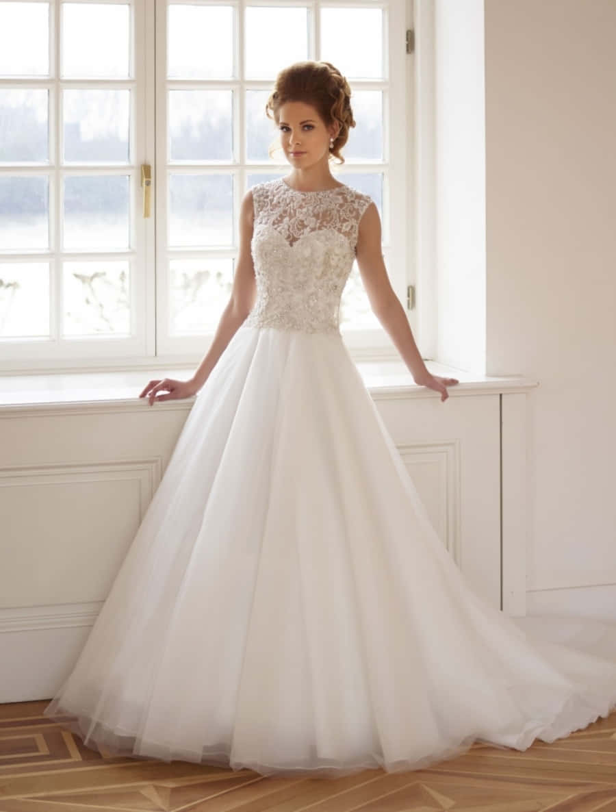 Wedding Dress 桌布 壁紙 — 一位新娘穿著白色蕾絲和薄紗婚紗，優雅地站在經典房間的明亮窗邊。