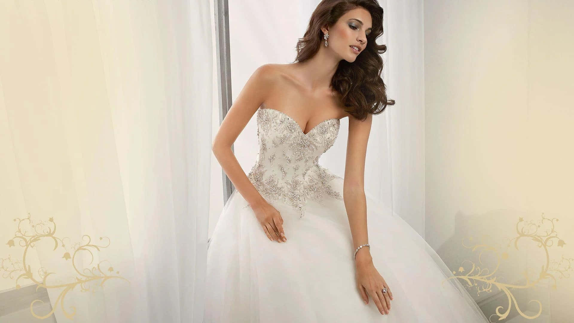 Wedding Dress 桌布 壁紙 — 一位新娘穿著華麗的白色無肩帶禮服，優雅地站在帶有金色花卉圖案的薄紗窗簾旁。