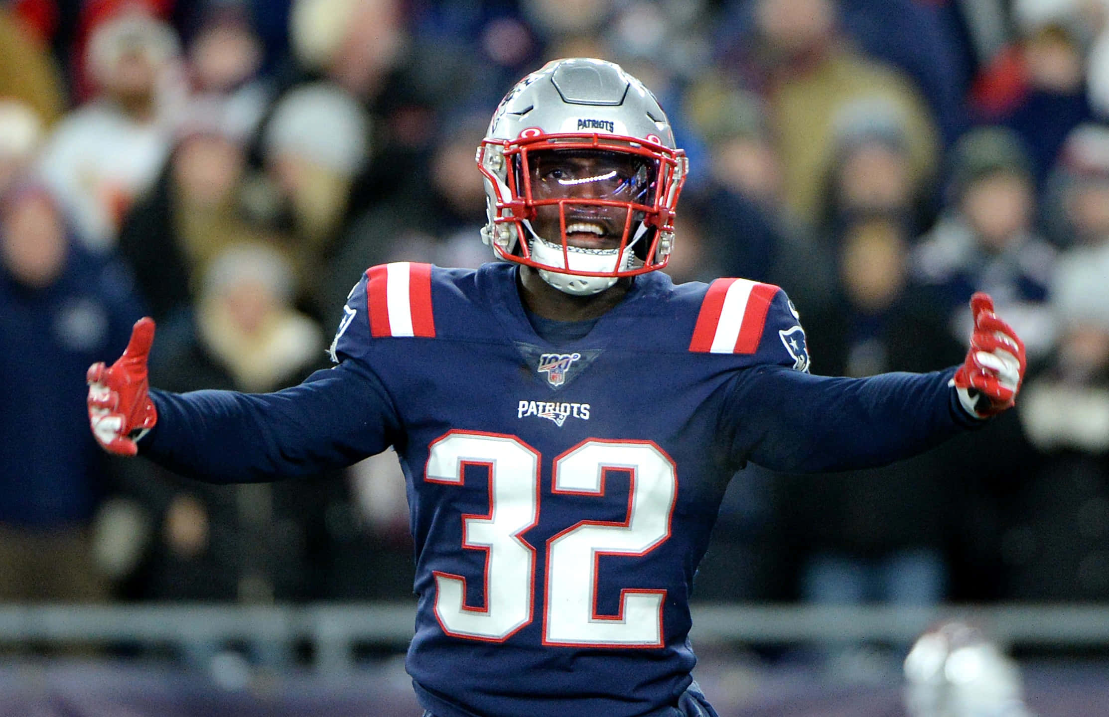 Devin Mccourty 桌布 壁紙 — 一位新英格蘭愛國者隊的32號美式足球員在球場上張開雙臂慶祝。