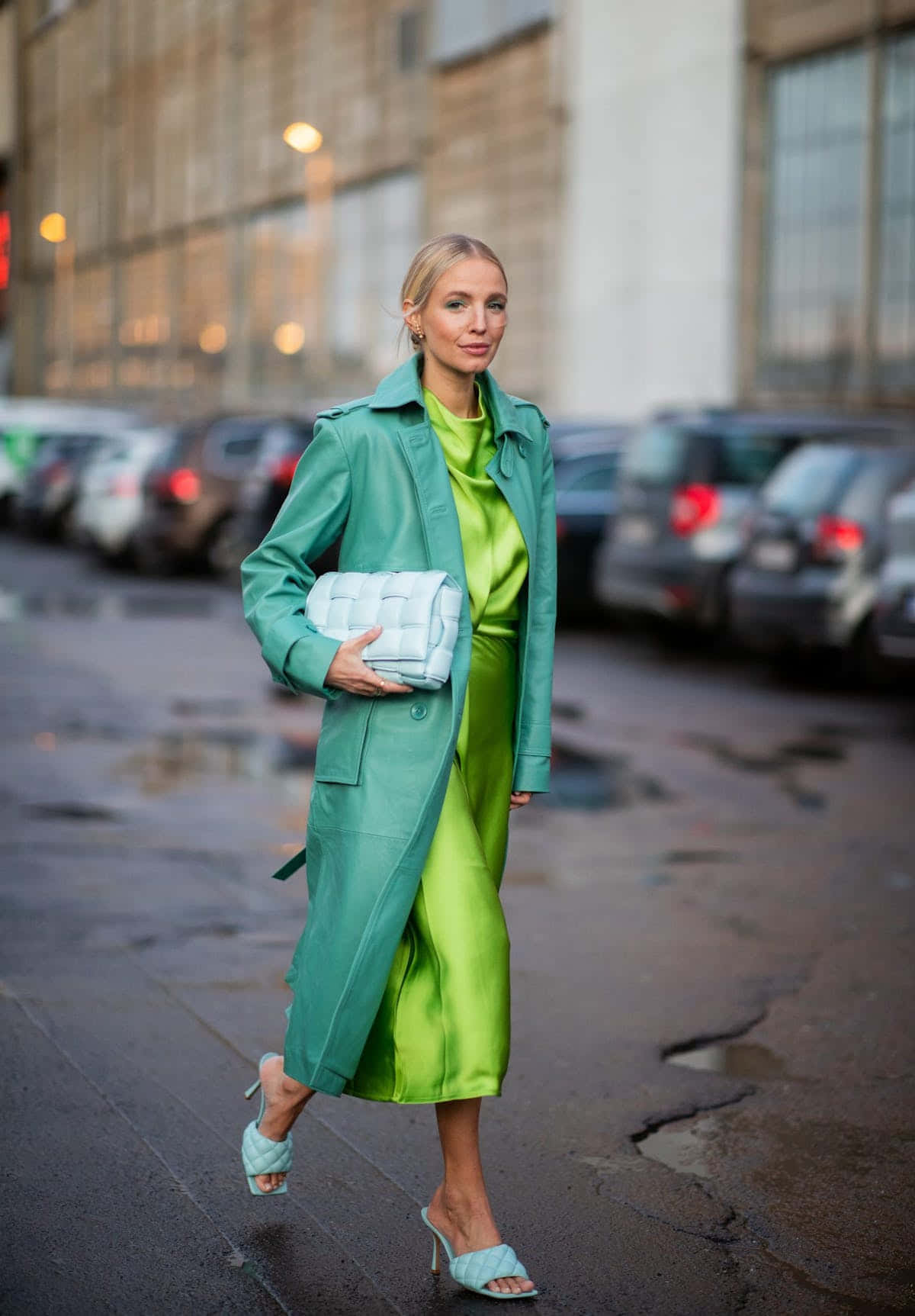 Green Fashion 桌布 壁紙 — 一位時尚女性自信地走在濕漉漉的城市街道上，身穿鮮綠色風衣和相配的緞面連衣裙。