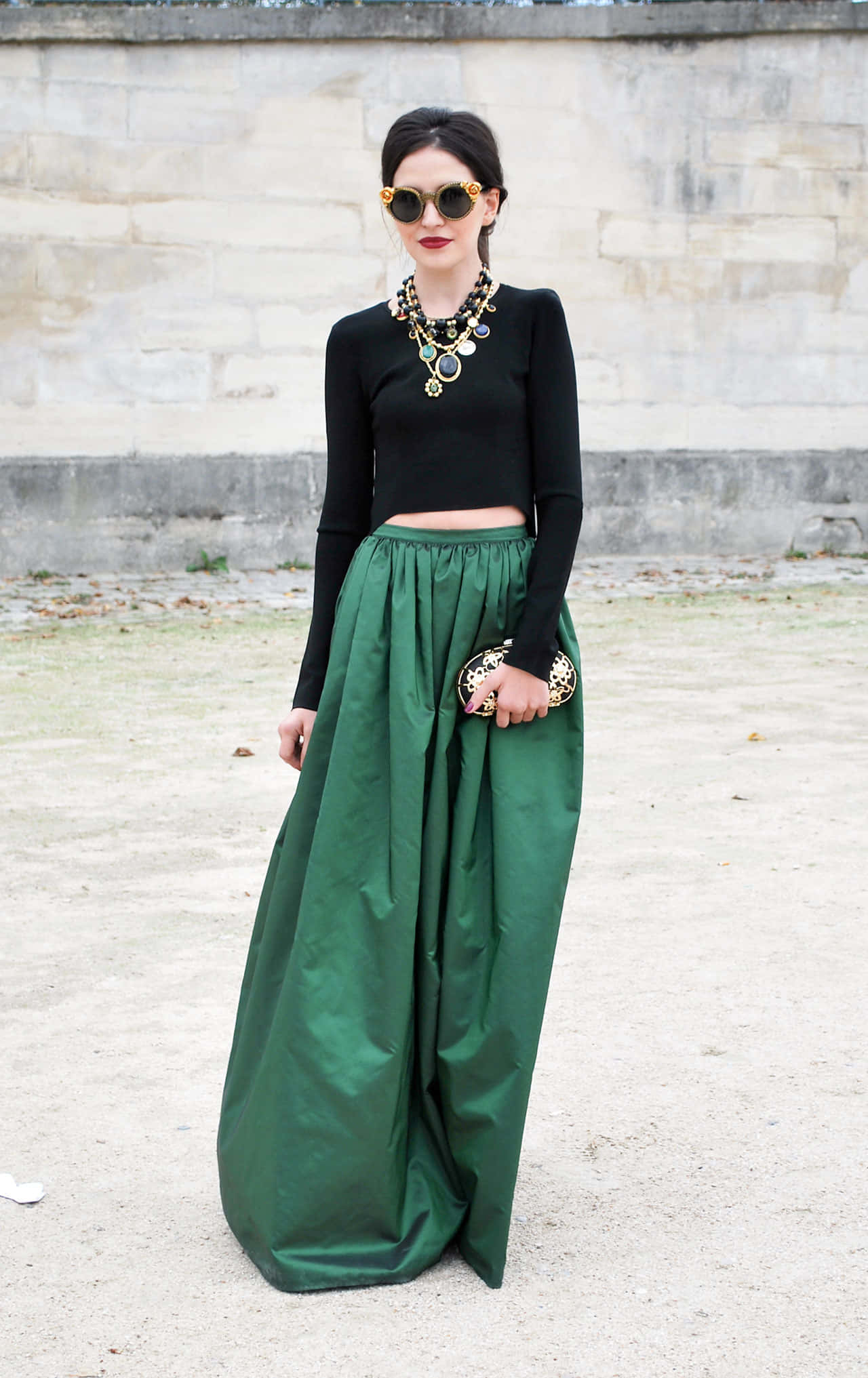 Green Fashion 桌布 壁紙 — 一位時尚女性身穿黑色短版上衣和翡翠綠色緞面寬腿褲，在風化的石牆前自信地擺姿勢。