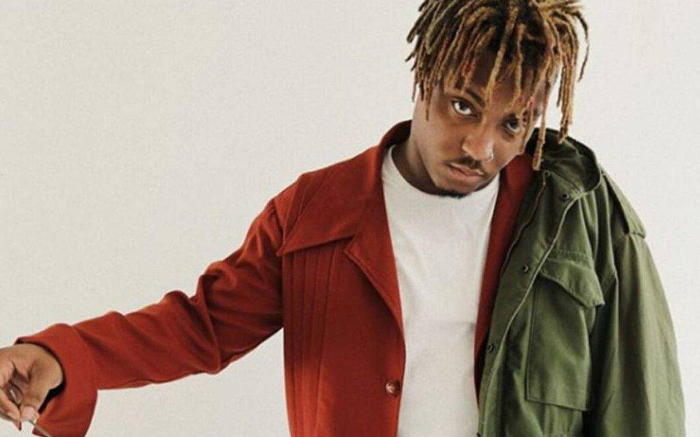 Juice WRLD 桌布 壁紙 — 一位時尚男士留著金色辮子，在白色背景前穿著紅色外套內搭綠色外套。