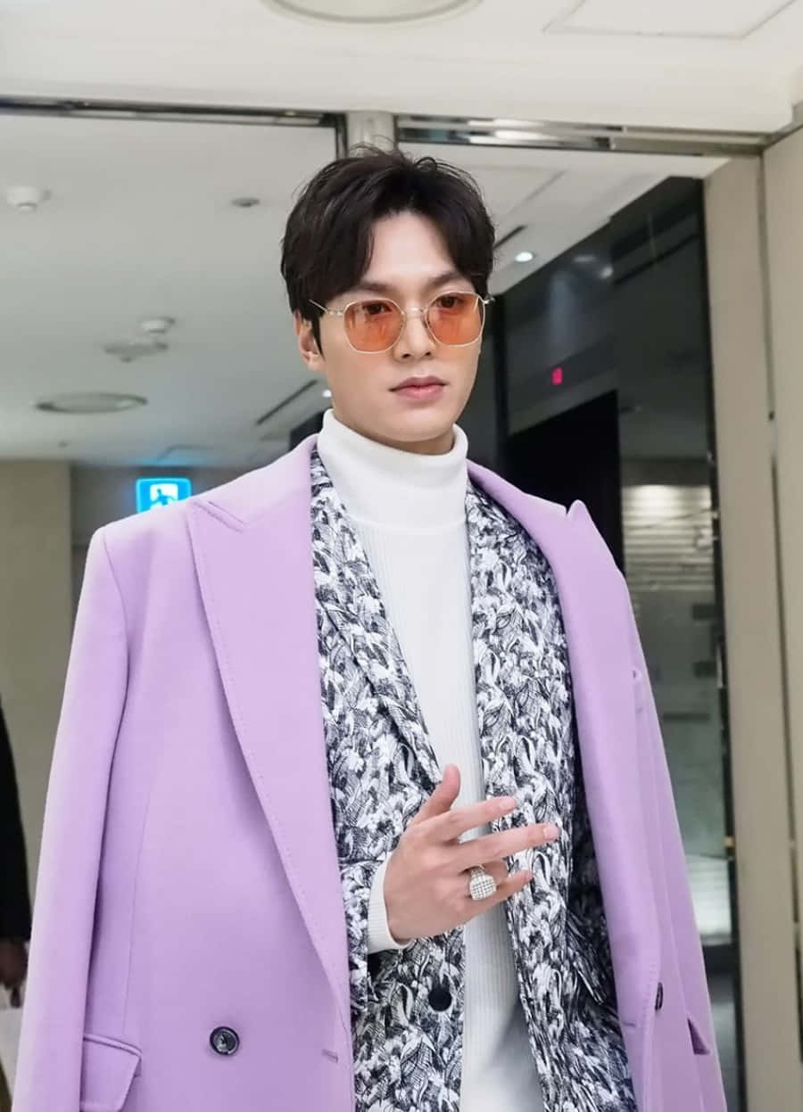 Lee Min Ho 桌布 壁紙 — 一位時尚男士身穿薰衣草色西裝外套和圖案圍巾，戴著橙色太陽眼鏡，在室內自信地擺姿勢。