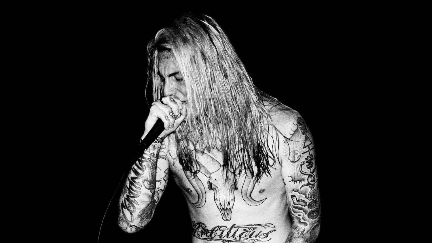 Ghostemane 桌布 壁紙 — 一位有紋身、長髮的音樂家，在純黑背景前，以高對比黑白風格對著咪高峰唱歌。
