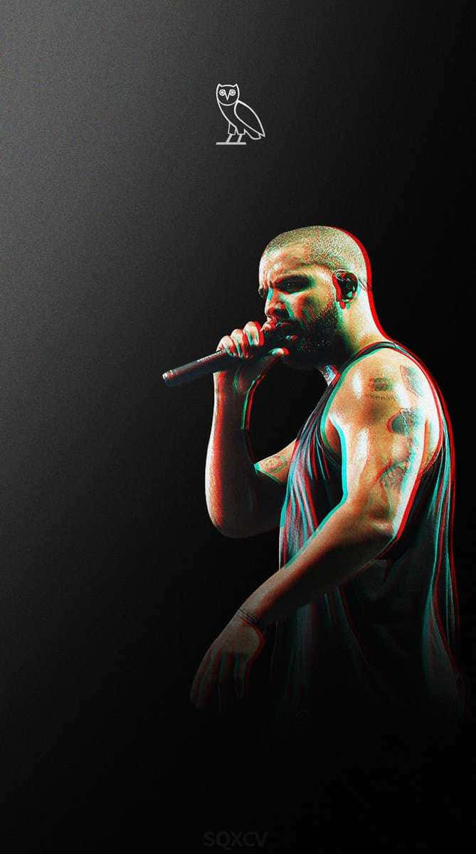 Drake 桌布 壁紙 — 一位有紋身的饒舌歌手在黑色背景帶有貓頭鷹標誌的環境中，於戲劇性的紅色和青色燈光下對著麥克風唱歌。