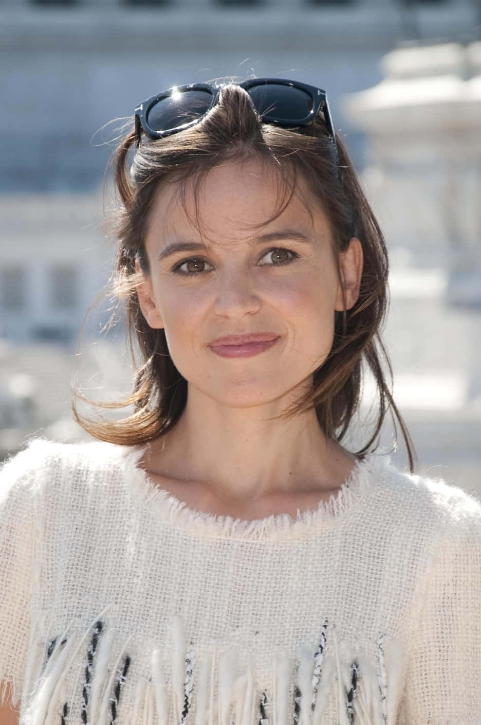 Elena Anaya 桌布 壁紙 — 一位棕色頭髮、太陽眼鏡架在頭上的女性，穿著質感白色流蘇毛衣，溫柔微笑。