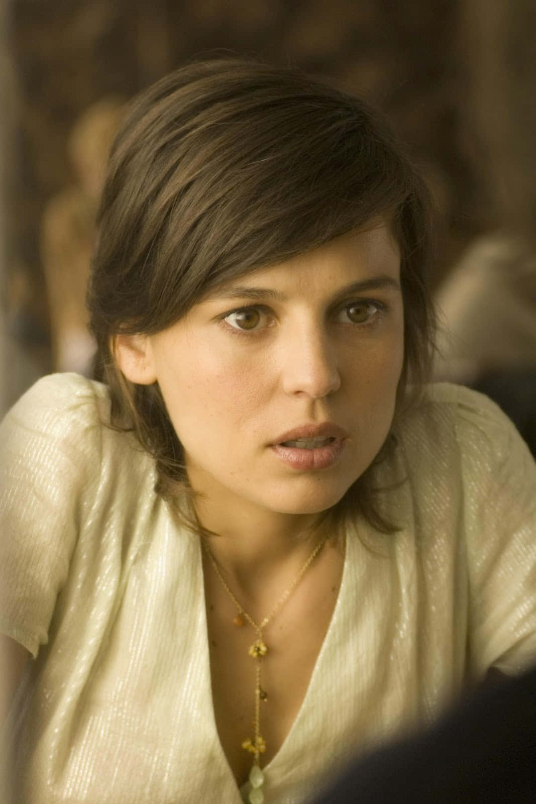 Elena Anaya 桌布 壁紙 — 一位棕色頭髮、身穿奶油色質感上衣的女性，專注地向前看的特寫肖像。