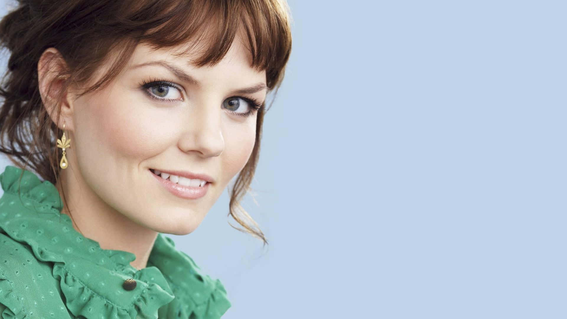 jennifer morrison 桌布 壁紙 — 一位棕色頭髮、身穿綠色襯衫的女性在淺藍色背景前溫柔微笑。